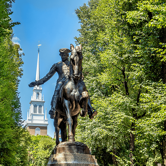 Historical statue with building in back in New England. Click to watch video.
