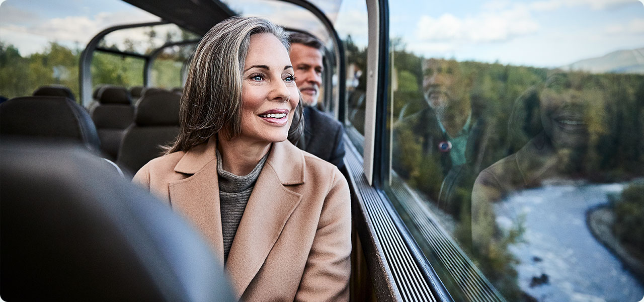 A woman and man enjoying the scenic Direct-to-the-Wilderness® rail service through Alaska.