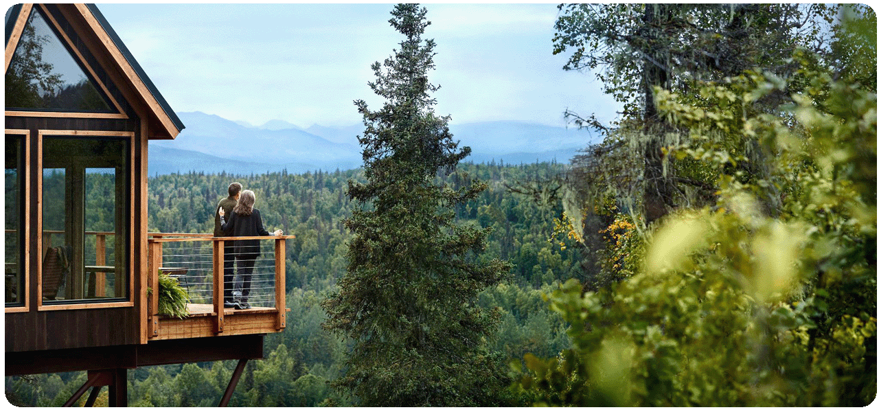 Couple enjoying the scenic view from a treehouse balcony at Mt. McKinley Princess Wilderness Lodge. Click here to learn more.